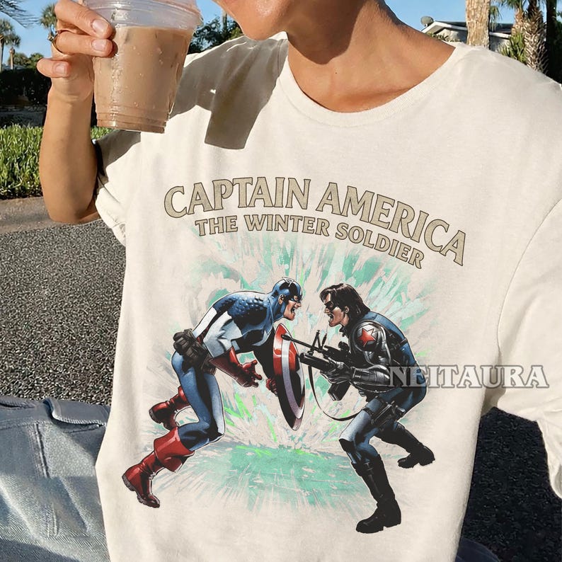 May include: Off-white t-shirt with a graphic of Captain America and the Winter Soldier in combat. The text "CAPTAIN AMERICA THE WINTER SOLDIER" is printed above the image in a vintage style.