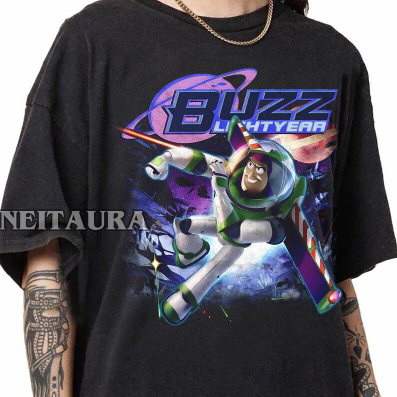 May include: Black t-shirt with a graphic of Buzz Lightyear in his spacesuit, with the words "Buzz Lightyear" in a retro font. The design includes a space scene with planets and stars.