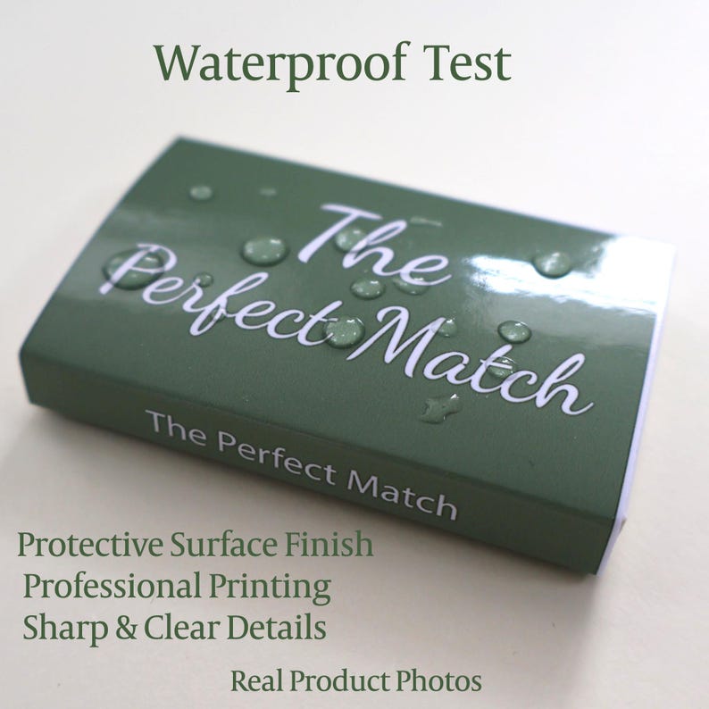 May include: A rectangular olive green box with the white text The Perfect Match printed on the top and side. The surface features a glossy finish with several clear water droplets resting on the top, demonstrating a protective coating.