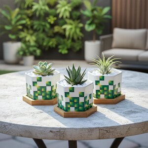 May include: Three white hexagonal planters with green and yellow pixelated designs, each holding a different succulent. The planters sit on wooden hexagonal saucers on a stone table. The background includes greenery and outdoor furniture.
