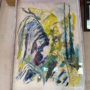 Pode incluir: Pintura abstrata em aquarela em uma moldura de madeira clara. A obra apresenta uma mistura de pinceladas azuis, amarelas, verdes e roxas, criando uma composição dinâmica. A pintura é emoldurada com uma moldura de madeira clara.