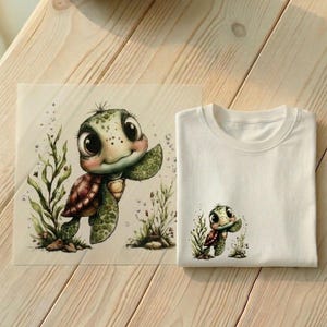 Könnte beinhalten: Weißes T-Shirt mit einem kleinen, farbenfrohen Cartoon-Schildkröten-Motiv. Neben dem Shirt befindet sich ein Druck des gleichen Schildkröten-Designs mit Seegras und Blasen. Die Schildkröte hat einen grünen Panzer und winkt. Der Hintergrund ist helles Holz.