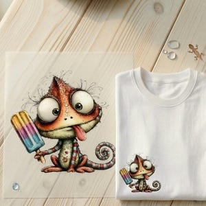 Könnte beinhalten: Ein weißes T-Shirt und ein Druck mit einem Cartoon-Chamäleon mit großen Augen und langer Zunge, das ein buntes Eis am Stiel hält. Das Chamäleon ist in Orange-, Rot- und Grüntönen gehalten. Der Druck befindet sich auf einer transparenten Kunststofffolie.