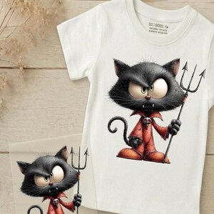 Könnte beinhalten: Ein weißes Kurzarm-T-Shirt mit einer Grafik einer schwarzen Katze im roten Teufelskostüm, die einen schwarzen Dreizack hält. Die Katze hat große Augen, ein Totenkopf-Emblem am Kragen und einen geringelten Schwanz. Das Innenetikett zeigt SOZ / GRÖSSE: 104.