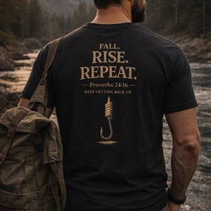 May include: Black t-shirt with the text "FALL. RISE. REPEAT." and a fishing hook graphic. The shirt also includes the Bible verse Proverbs 24:16. A person wearing a cap and carrying a backpack stands near a river.