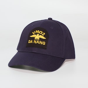 Op de afbeelding: Een witte keramische mok met een zwarte handgreep en de tekst "But First, Coffee" in een vetgedrukte, zwarte letter. De mok staat tegen een vage achtergrond, wat een gezellige setting suggereert.