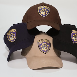 Op de afbeelding: Een witte keramische mok met een zwart handvat en de tekst "But First, Coffee" in een zwarte, handgeschreven lettertype. De mok staat op een wit oppervlak.