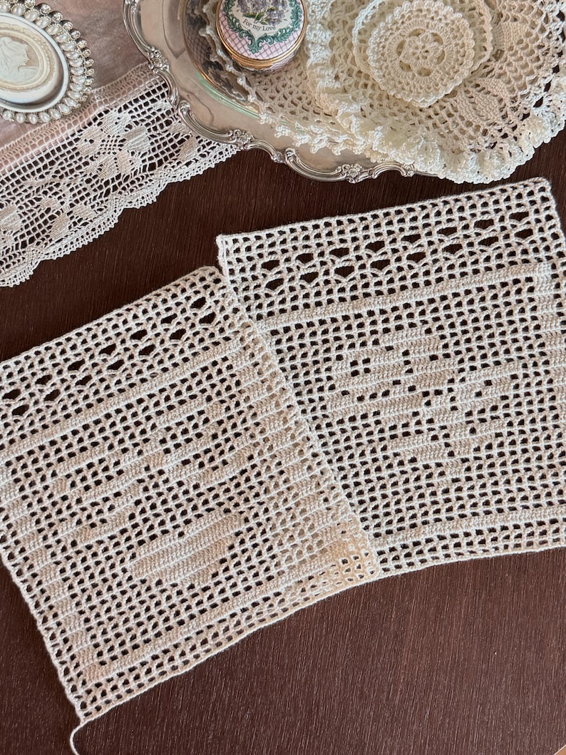 May include: Two square off-white crochet doilies featuring an intricate openwork grid pattern with a solid central motif. The handmade lace pieces display a delicate texture and are crafted with fine thread, showcasing a repeating geometric design.
