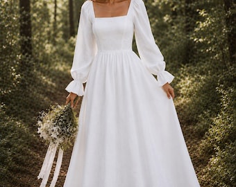 May include: A floor-length white dress with long, billowy sleeves featuring ruffled cuffs and a square neckline. The bodice is fitted, transitioning into a full, flowing skirt. The fabric has a subtle, uniform texture throughout the garment.