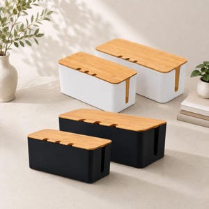 May include: Four rectangular cable management boxes with removable bamboo lids. Two boxes are white and two are black. Each box features a vertical side slot and three small circular cutouts along the top edge of the lid for organising cords.