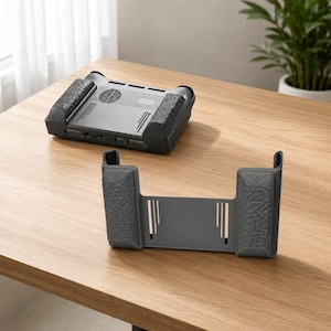 May include: A dark gray laptop stand with a matching phone holder. The laptop stand has a rectangular shape with a fan and several ports. The phone holder is a dark gray color with a rectangular shape and two vertical slots.