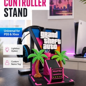 May include: A black controller stand featuring a large letter V with the Grand Theft Auto logo, two green palm trees, and a pink base. The stand includes a small sign with the text WANTED GAMERTAG and five yellow stars, designed for gaming consoles.