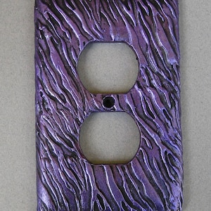 May include: Purple and black textured outlet cover with a wavy pattern.