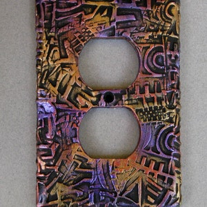 May include: A decorative outlet cover with a textured, abstract design in shades of purple, gold, and black.