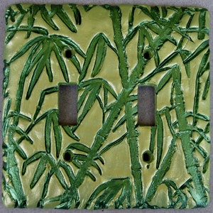 May include: A light green and gold double light switch cover with a raised bamboo design.