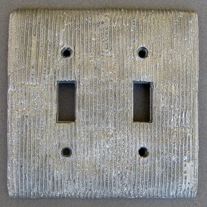 May include: A silver light switch plate with a textured surface and two toggle switches.