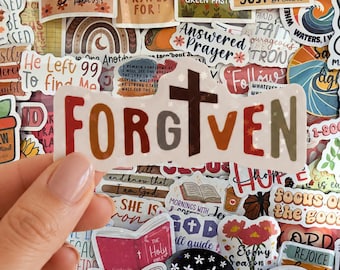 May include: A die-cut vinyl sticker featuring the word FORGIVEN in a multi-colored, earthy palette of red, orange, brown, and olive green. The letter I is replaced by a dark brown cross, and the entire design is accented with small white stars.