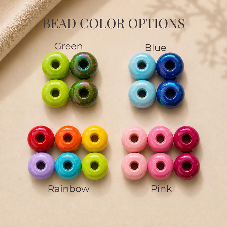 May include: A collection of round, donut-shaped beads arranged in groups labeled BEAD COLOR OPTIONS. The sets include Green, Blue, Rainbow, and Pink variations, featuring glossy, matte, and iridescent finishes in various vibrant colors.