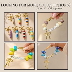 May include: A collection of gold-toned metal keychains featuring colorful beads and charms. Some keychains include white letter beads spelling names like BUNCO, AUNTIE, and GEMMA, while others feature charms like bows, sports balls, and letters.