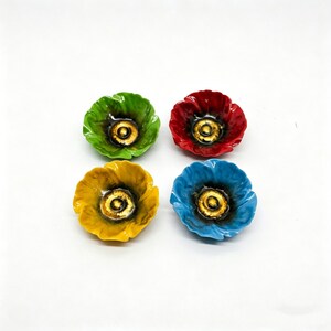 May include: Four ceramic poppy-shaped dishes in vibrant colors: green, red, yellow, and blue. Each dish features a golden center and a glossy finish, perfect for holding small items or as decorative accents.