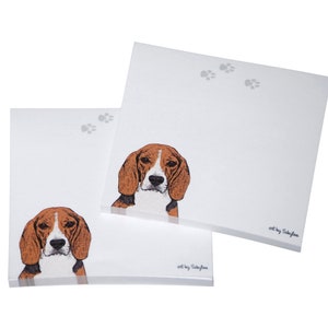 May include: Two white notepad sets with a brown and white beagle dog illustration. Each notepad has a paw print design and the text "art by Sakyfee".
