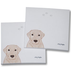 May include: Two white notepads with a brown Labrador Retriever illustration on each. The top notepad has a paw print design and the text "art by Sakylaa". The bottom notepad has the text "art by Sakylaa".