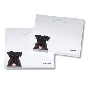 May include: Two white square notepads with a black dog illustration and paw prints. The dog has a pink tongue sticking out. The text "art by Sabylaa" is printed on the bottom right corner of the notepads.