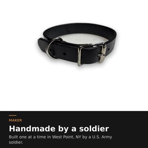 May include: A black leather collar featuring a silver-toned metal buckle and a D-ring. The text below reads: MAKER Handmade by a soldier Built one at a time in West Point, NY by a U.S. Army soldier.