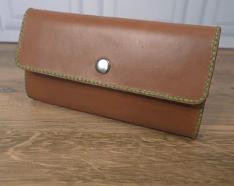 May include: A rectangular tan leather wallet featuring a single silver-toned metal snap button closure. The edges of the wallet are stitched with thick, bright lime green thread, providing a distinct contrast to the smooth brown leather surface.