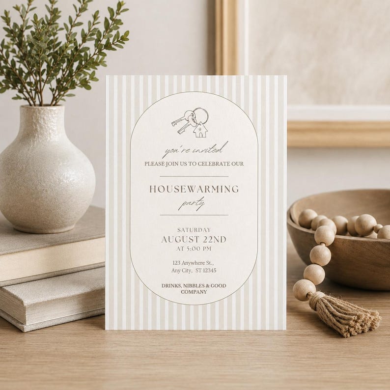 Puede incluir: Una tarjeta de invitaci&oacute;n rectangular para una fiesta de inauguraci&oacute;n con un patr&oacute;n de rayas verticales en beige y blanco. El centro contiene un marco ovalado con un dibujo lineal de llaves y una casa, seguido del texto: you're invited, HOUSEWARMING party, SATURDAY AUGUST 22ND AT 5:00 PM, 123 Anywhere St., Any City, ST 12345, DRINKS, NIBBLES & GOOD COMPANY.