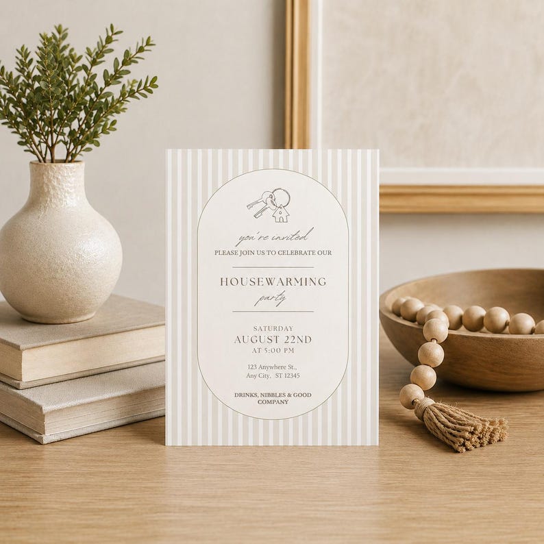 Puede incluir: Una tarjeta de invitaci&oacute;n rectangular para una fiesta de inauguraci&oacute;n con un patr&oacute;n de rayas verticales en beige claro y blanco. El centro muestra un marco arqueado con un dibujo de llaves y una casa, con texto detallando la fecha y el lugar.