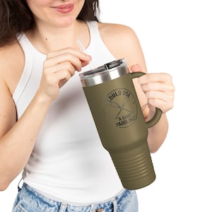 Pode incluir: Caneca de viagem verde-oliva com alça e tampa prateada. A caneca tem o texto "I COULD USE A GOOD PADDLING" em um design circular. Uma palhinha transparente é inserida na tampa.