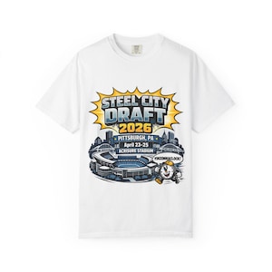 Puede incluir: Camiseta blanca con un gráfico colorido para el Draft de Steel City 2026 en Pittsburgh, PA. El diseño incluye el texto "STEEL CITY DRAFT 2026", el horizonte de la ciudad y el estadio Acrisure. También se incluye un reloj de dibujos animados.