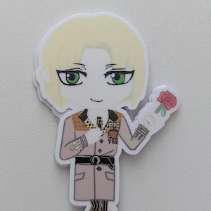 Puede incluir: Una pegatina troquelada con un personaje de dibujos animados con pelo rubio y ojos verdes, que lleva un abrigo color canela y sostiene una rosa roja. El personaje sonríe ligeramente, sobre un fondo blanco.