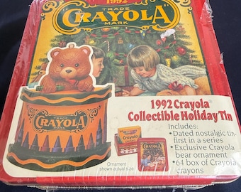 May include: A 1992 Crayola Collectible Holiday Tin, featuring a teddy bear ornament and a Christmas scene. The tin is red with gold and orange accents, and includes a 64-box of Crayola crayons.