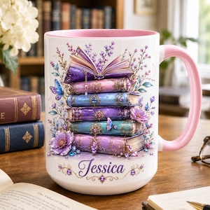 May include: A white ceramic mug with a pink interior and handle, featuring a stack of five illustrated books in shades of purple and blue, decorated with floral accents, butterflies, and jewels, with the name Jessica printed in purple script.
