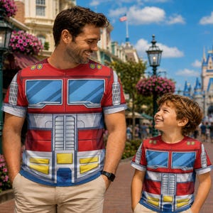 May include: Two short-sleeved t-shirts featuring a graphic print of a red, blue, and silver robot chest plate design. The shirts display a pattern of blue windshields, silver grill details, and yellow accents on a red background with short sleeves.