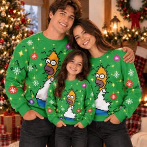 May include: A bright green long-sleeve crewneck sweatshirt featuring a pixelated graphic of Homer Simpson from The Simpsons, surrounded by a festive pattern of white snowflakes, yellow starbursts, and red, pink, and purple Christmas ornaments.