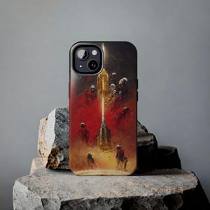 May include: Black iPhone case featuring a sci-fi art design. The artwork depicts figures in red suits against a backdrop of a golden structure and a red, smoky atmosphere. The case has a black border and camera cutout.
