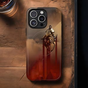 May include: A phone case featuring a warrior figure on a red and orange background. The case has a clear border and a design that evokes a sense of adventure. The phone case is on a wooden surface.