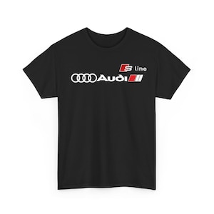 Può includere: Una t-shirt nera a maniche corte con il logo Audi bianco composto da quattro anelli intrecciati e la scritta Audi. Sopra il testo si trova un quadrato rosso contenente una S bianca, seguito dalla parola line in bianco e due strisce.