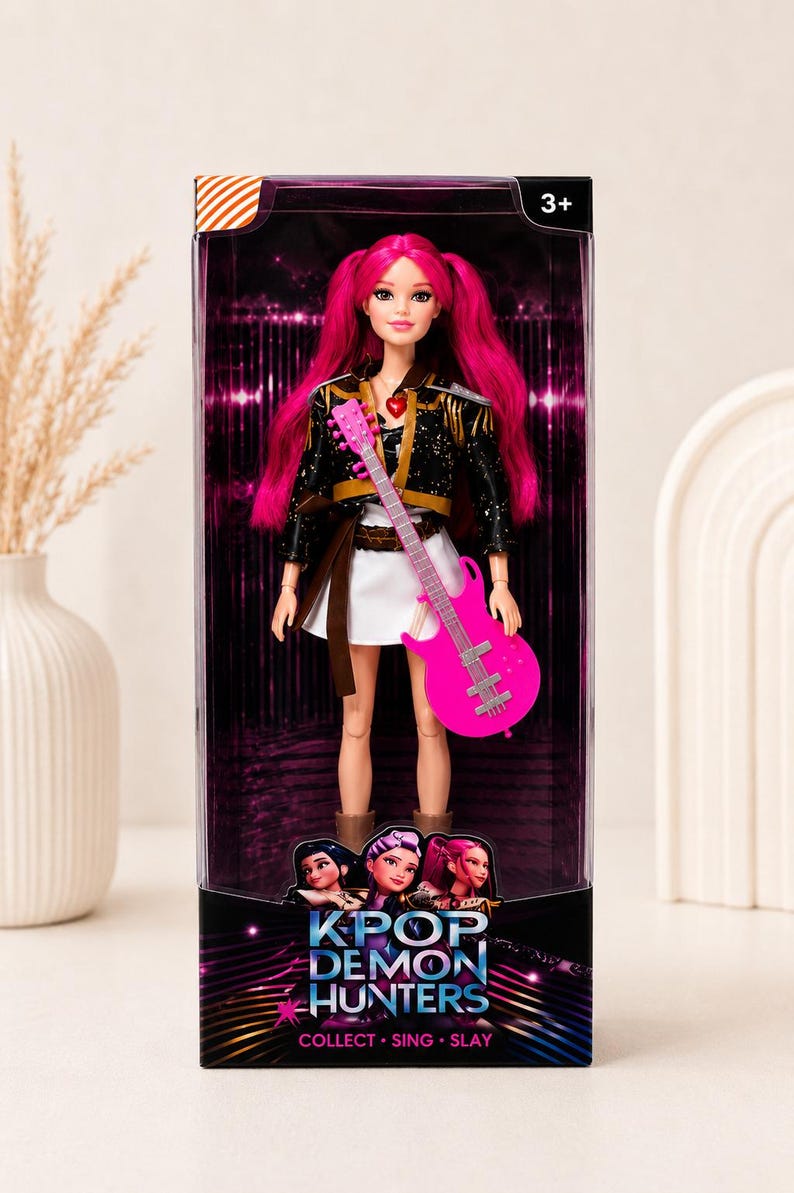 May include: A doll with bright pink hair and a matching guitar, dressed in a black jacket and white skirt. The doll is packaged in a box with the text "KPOP DEMON HUNTERS" and the tagline "COLLECT. SING. SLAY."