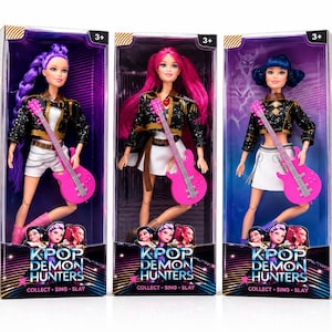May include: Three K-Pop Demon Hunters dolls in boxes. Each doll has a different hair color: purple, pink, and blue. They wear black and gold jackets, white skirts, and pink boots. Each doll holds a pink guitar. The boxes have the text "KPOP DEMON HUNTERS" and "COLLECT &bull; SING &bull; SLAY."