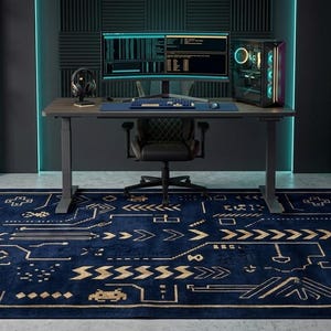 May include: A rectangular area rug featuring a deep blue background with a gold-coloured geometric pattern resembling circuit board lines, arrows, and gaming icons. The design includes stylised shapes, crosses, and small pixelated figures.