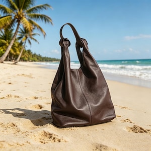 May include: A dark brown leather hobo bag with a slouchy, unstructured silhouette, featuring a single integrated handle with knotted details at the top and a vertical seam running down the center of the front panel, crafted from smooth, matte leather.