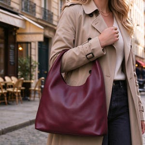 Peut inclure: Un sac hobo bordeaux profond à la finition lisse, doté d'une large bandoulière intégrée et d'une silhouette spacieuse et non structurée. Le sac est fabriqué dans un matériau de couleur unie et présente un design épuré sans aucune garniture visible.