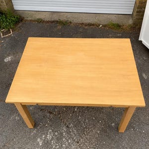 Könnte beinhalten: Ein rechteckiger Holztisch mit hellbraunem Finish. Der Tisch hat vier gerade Beine und eine glatte Oberfläche. Der Tisch ist etwa 152 cm lang und 76 cm breit.
