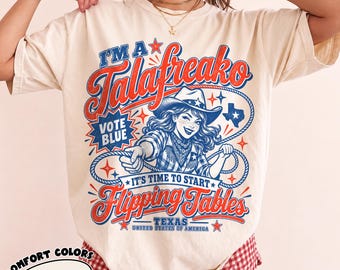 May include: An ivory t-shirt featuring a graphic print with the text I'M A Talafreako, VOTE BLUE, IT'S TIME TO START Flipping Tables, TEXAS, UNITED STATES OF AMERICA. The design includes a cowgirl holding a lasso, stars, and a Texas state shape.