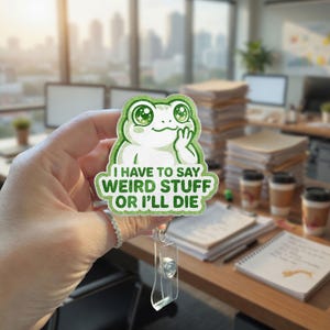 May include: A green and white frog-shaped sticker with the text "I HAVE TO SAY WEIRD STUFF OR I'LL DIE." The sticker has a clear plastic retractable badge holder attached. The frog has large, sparkling eyes and is giving a thoughtful gesture.