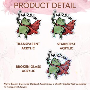 May include: A sticker sheet featuring three frog illustrations with the word "Huzzah". The frogs are green and wear red capes, holding swords. The text "Product Detail", "Transparent Acrylic", "Starburst Acrylic", and "Broken Glass Acrylic" are also visible.